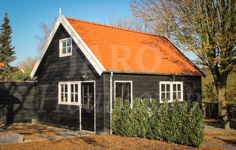 Houten bijgebouw met zadeldak en dakpannen in de tuin