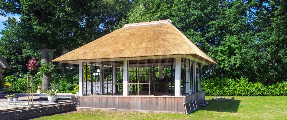 Oranjerie in de tuin uitgevoerd met rieten kap