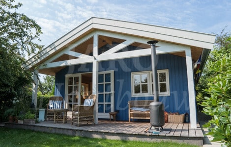 Een houten chalet met blauwe gevelbekleding (verticaal aangebracht)