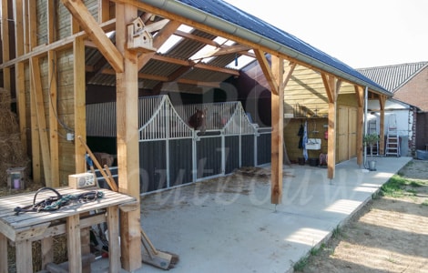 Foto van binnenzijde houten paardenstal met veel ruimte