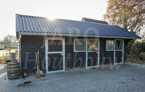 Houten paardenstal met zwarte golfplaten