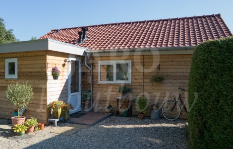 Een zorgwoning van hout in de tuin met aanbouw