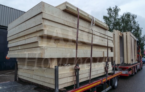 Afgeladen vrachtwagen met prefab houten gevelwanden