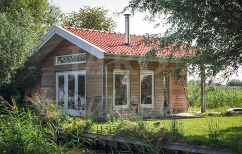 Een houten chalet met blauwe gevelbekleding (verticaal aangebracht)